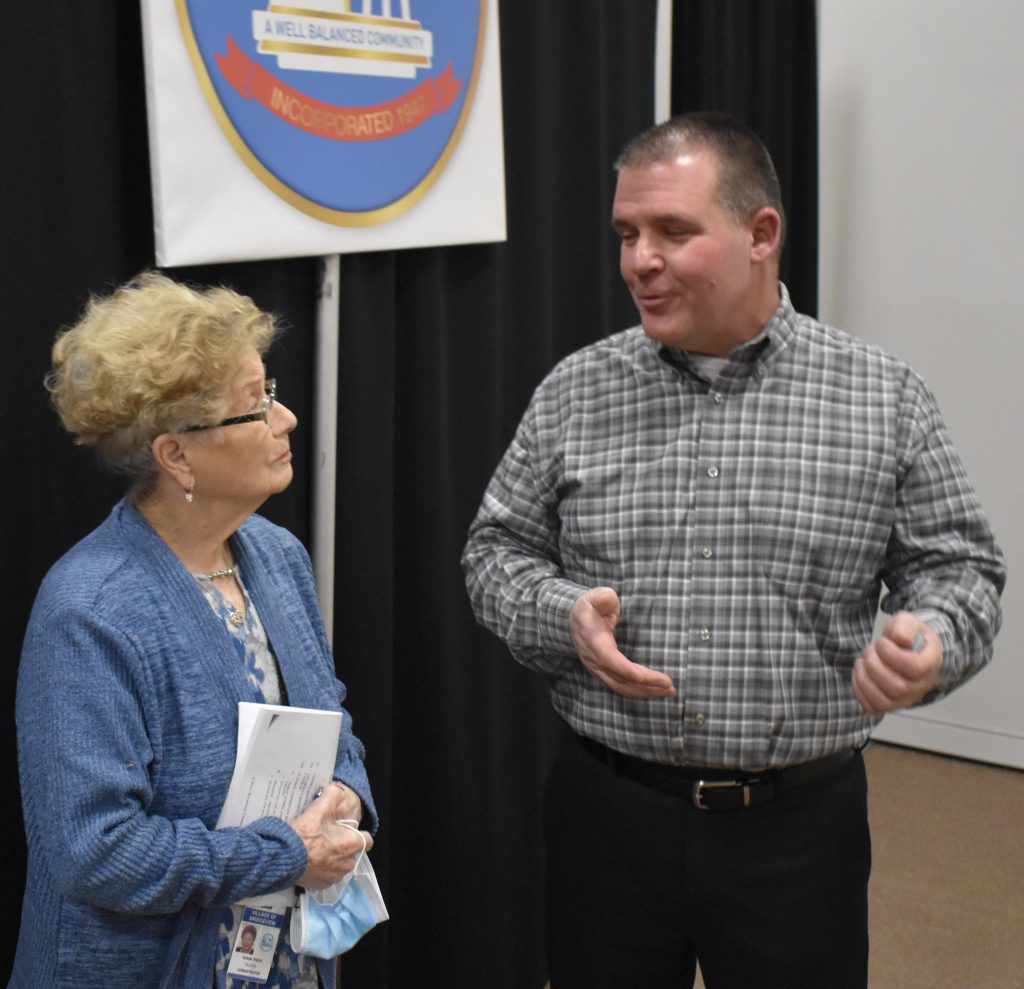 Michael Medeisis chats with village Trustee Norma Pinion after the board promoted himto the rank of fire battalion chief. (Photo by Steve Metsch)