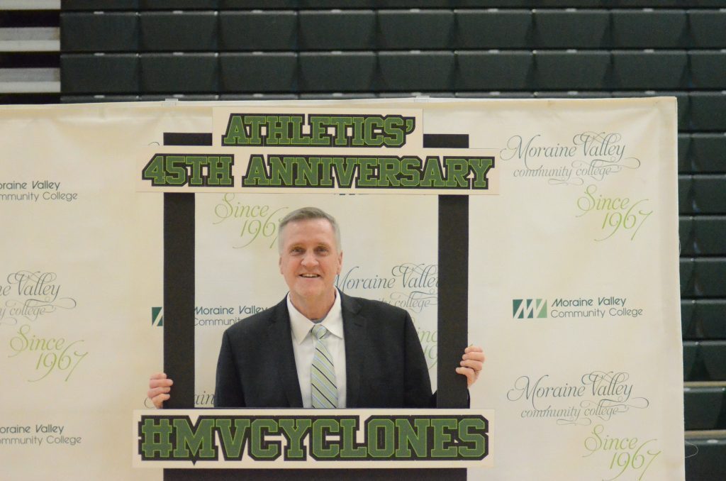 Moraine Valley Athletics Director Bill Finn has a little fun with a sign at the school's celebration of 45 years of offering sports. Photo by Jeff Vorva
