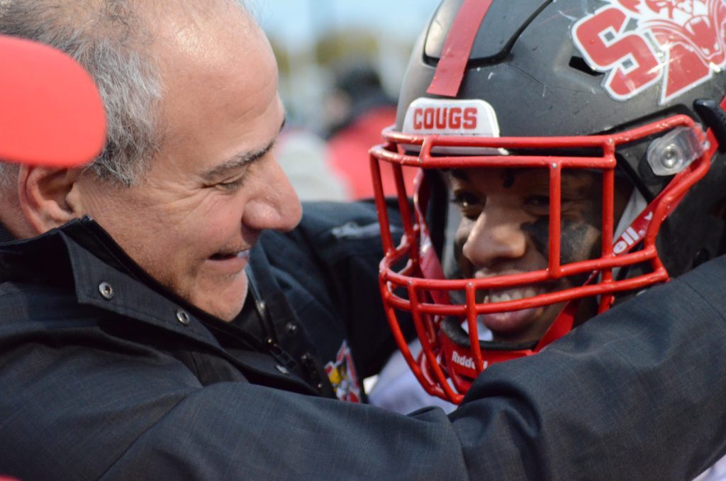 SXU football coach Mike Feminis hugs Amari Venerable after the running back scored the game-winning TD in overtime St. Francis in Joliet last year to qualify for the NAIA playoffs. The Cougars are ranked 11th in the country in the preseason. Photo by Jeff Vorva