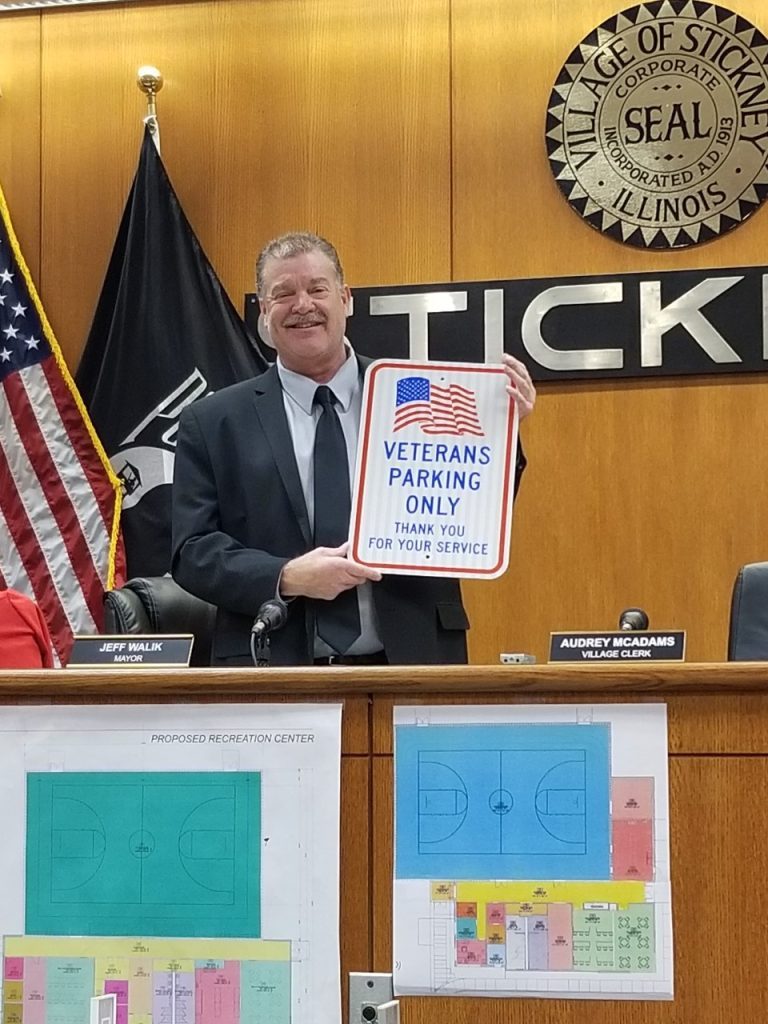 Stickney Mayor Jeff Walik holds up a Veterans Parking Only sign that will be installed at various village locations (Photo by Carol McGowan)