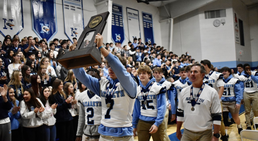Team captain Zach Hayes holds the trophy as Coach Tim Racki and the Roadrunners celebrate the school’s fourth state football championship in nine seasons, and first since 2018. (Photos by Steve Metsch) 