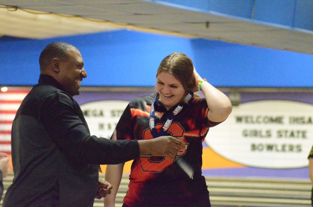 Glenbard East Athletic Director D'Wayne Bates, a former Chicago Bears wide receiver, presents a medal to Shepard's Kahlen Ranson at the state bowling meet on Feb. 18. Ranson placed fifth at the tournament. Photo by Jeff Vorva