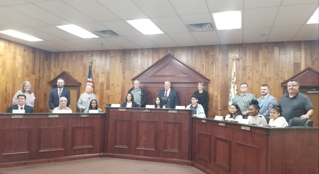 Justice village officials stand behind the junior officials who filled in for them at the February 27 village board meeting. (Photo by Carol McGowan)