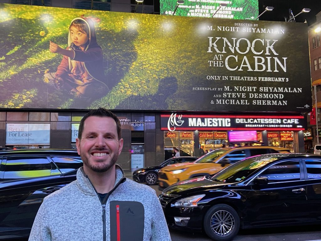 Palos Park native Steve Desmond in front of a marquee banner advertising the movie "A Knock at the Cabin," which he co-wrote. (Supplied photos)