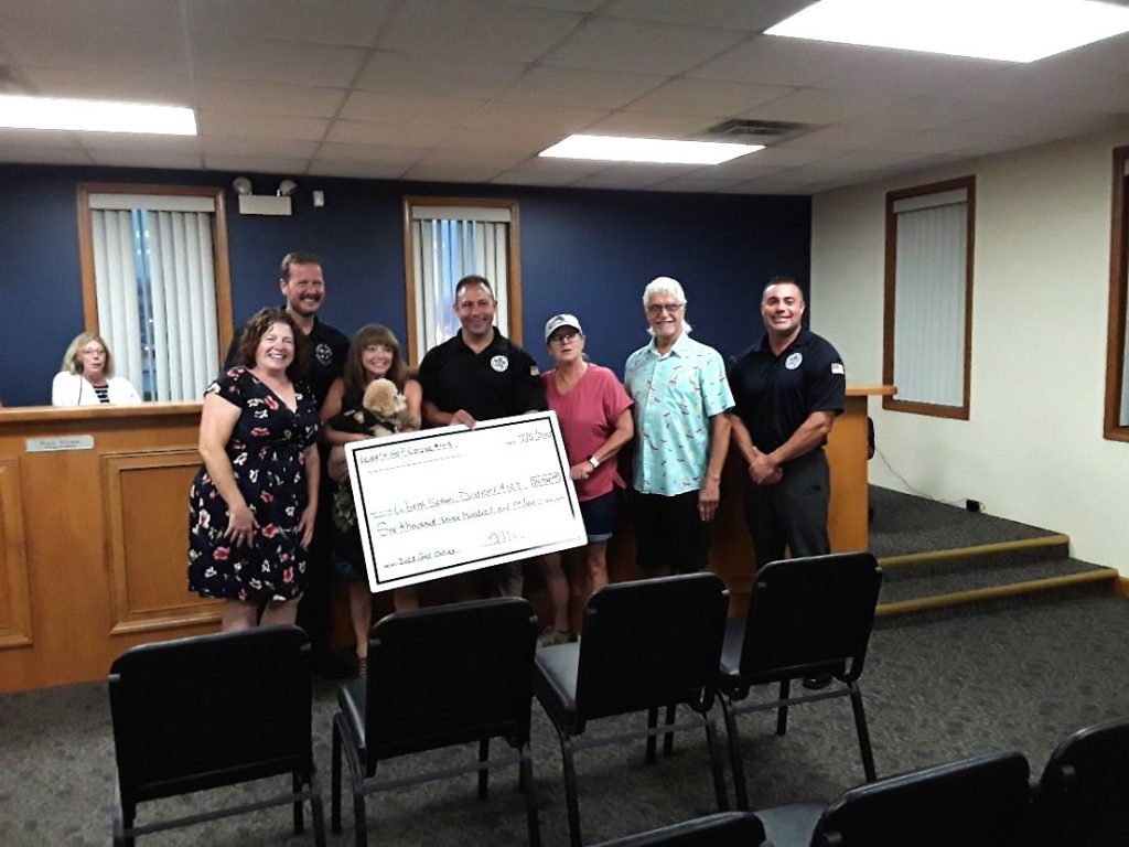 Sgt. Mike Cozzi (fourth from left) presented a $6,700 check to members of the Worth School District 127 board from proceeds raised during the annual FOP golf outing at Water's Edge Golf Course. Police Chief Tim Denton is at far right. The check was presented during the Worth Village Board meeting Wednesday night. (Photo by Joe Boyle)